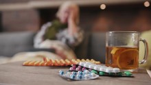 Close Up Of Many Different Spinning Drugs Older Woman Drink Tea Lying On Sofa Fever In Home Feel Unhappy Flu Sick Adult Cold Illness Person Sickness Virus Portrait Slow Motion Pills