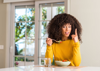 Poster - African american woman eating pasta salad surprised with an idea or question pointing finger with happy face, number one