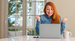 © Krakenimages.com - Redhead woman using computer laptop at home screaming proud and celebrating victory and success very excited, cheering emotion
