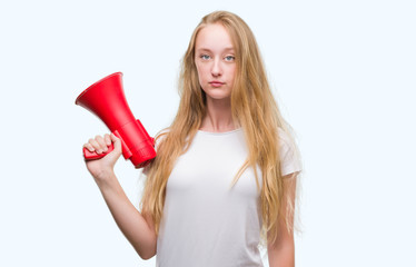 Canvas Print - Blonde teenager woman holding megaphone with a confident expression on smart face thinking serious