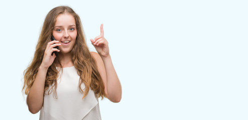 Sticker - Young blonde woman using smartphone surprised with an idea or question pointing finger with happy face, number one