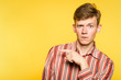 © golubovy - look there. funny comic man pointing sideways with a hand. portrait of a young guy on yellow background. free space for advertisement.