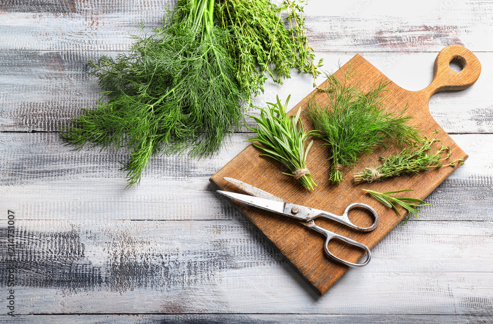 Fresh herbs with scissors on wooden background