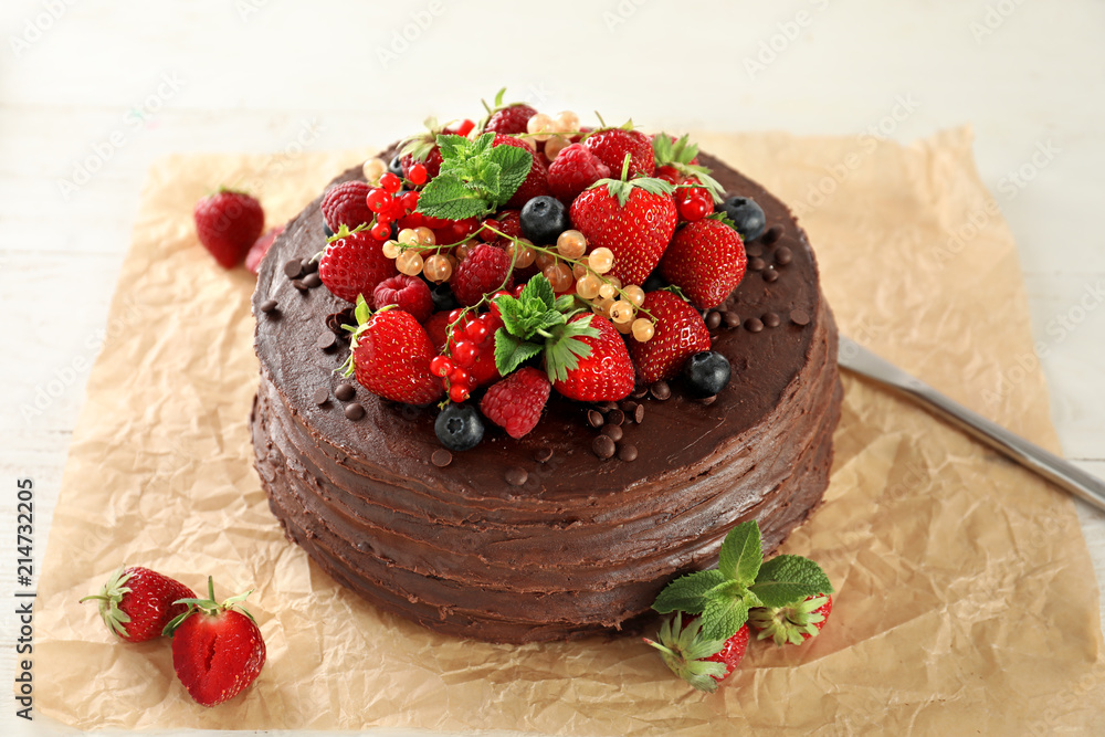 Tasty chocolate cake decorated with berries on table