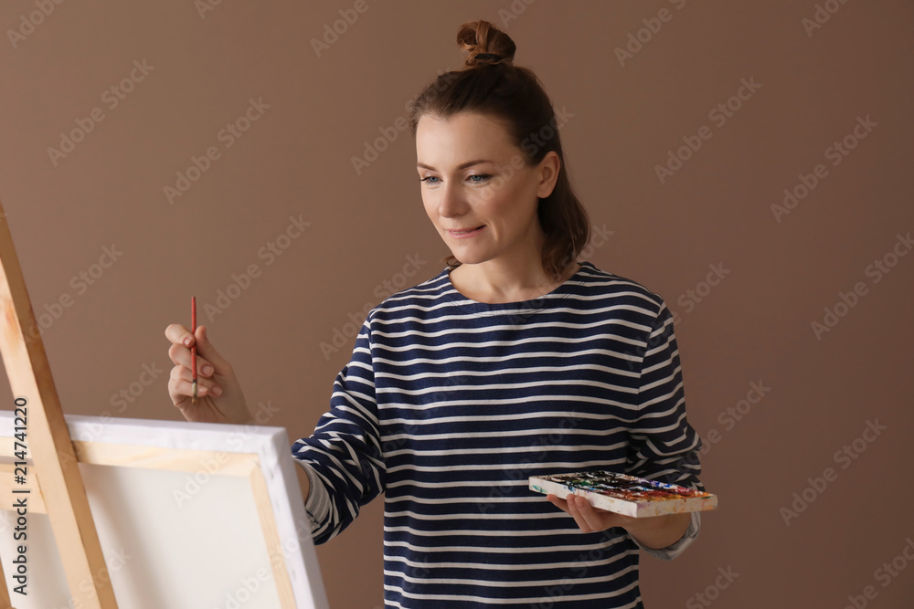 Female artist painting on color background