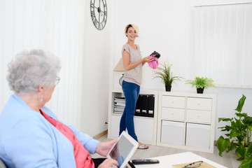 cheerful young girl helping with household chores an elderly woman at home