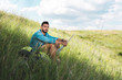 © LIGHTFIELD STUDIOS - male traveler sitting with backpack and map on green meadow