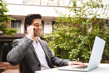 Wall Mural - Smiling young businessman dressed in suit talking