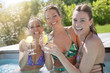 © goodluz - Girl friends in swimming-pool drinking cocktails