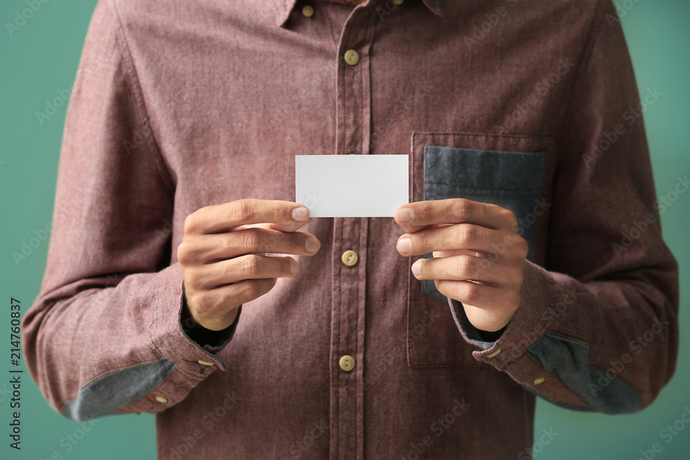 Man with business card on color background, closeup