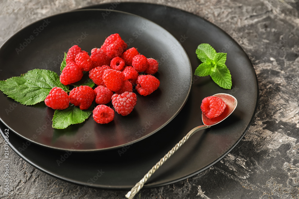Plates with ripe aromatic raspberries on table