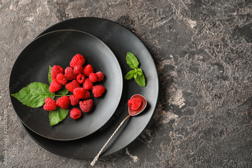Plates with ripe aromatic raspberries on table