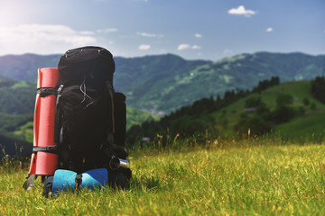 traveler backpack stand on grass in spring mountains