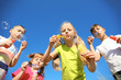 © Pixel-Shot - Cute little children blowing soap bubbles on blue sky background