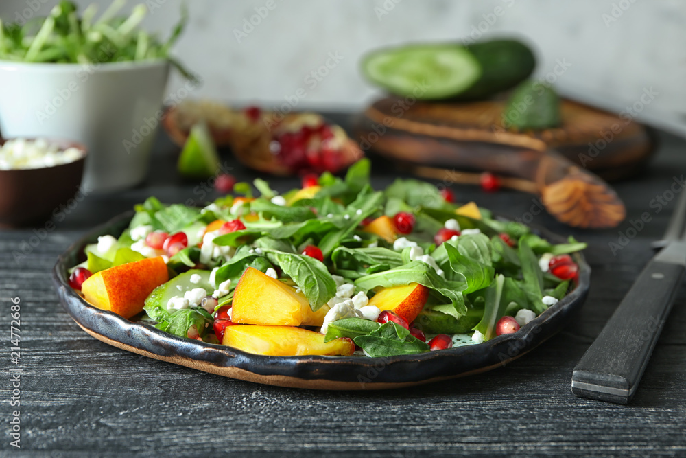 Plate with delicious healthy fresh salad on wooden table