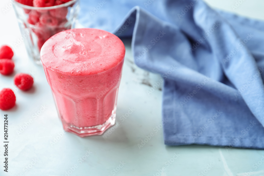 Glass with tasty raspberry smoothie on light table
