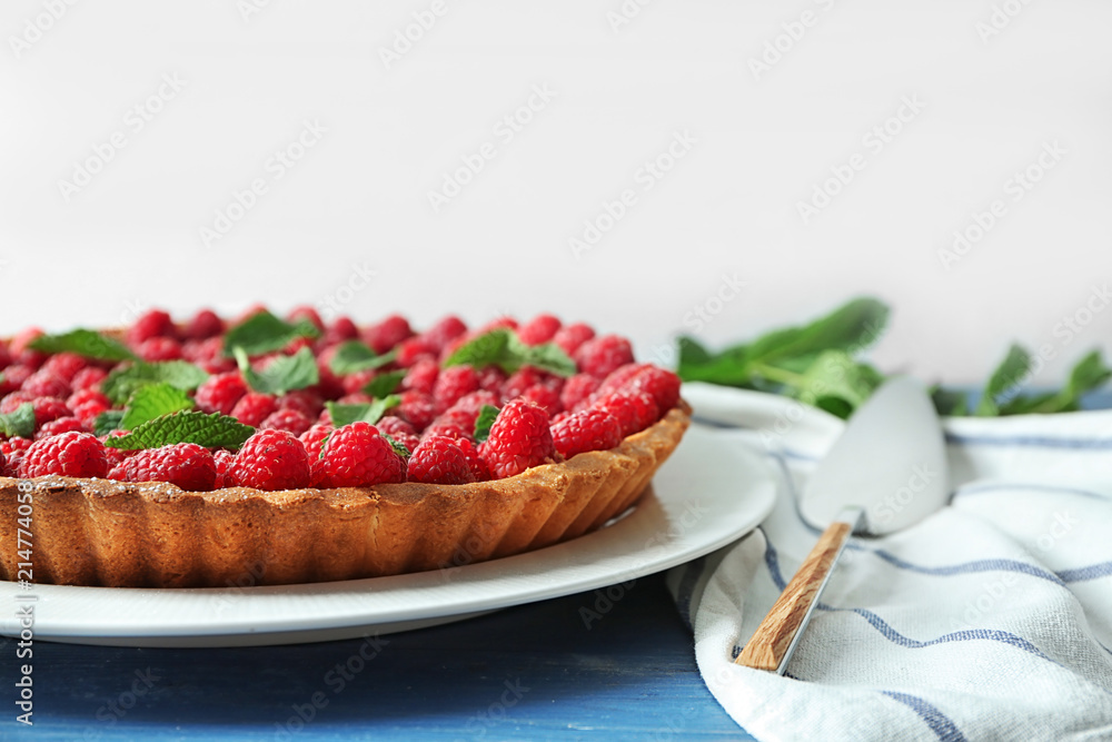 Tasty pie with fresh raspberries on color table
