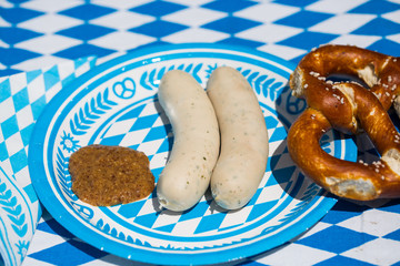 white sausage with sweet mustard and pretzel on blue white plate