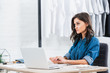 © LIGHTFIELD STUDIOS - attractive female fashion designer working at table with laptop
