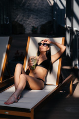 Wall Mural - Beautiful woman with glamour make up in stylish black swimwear. Drink glass cocktail.