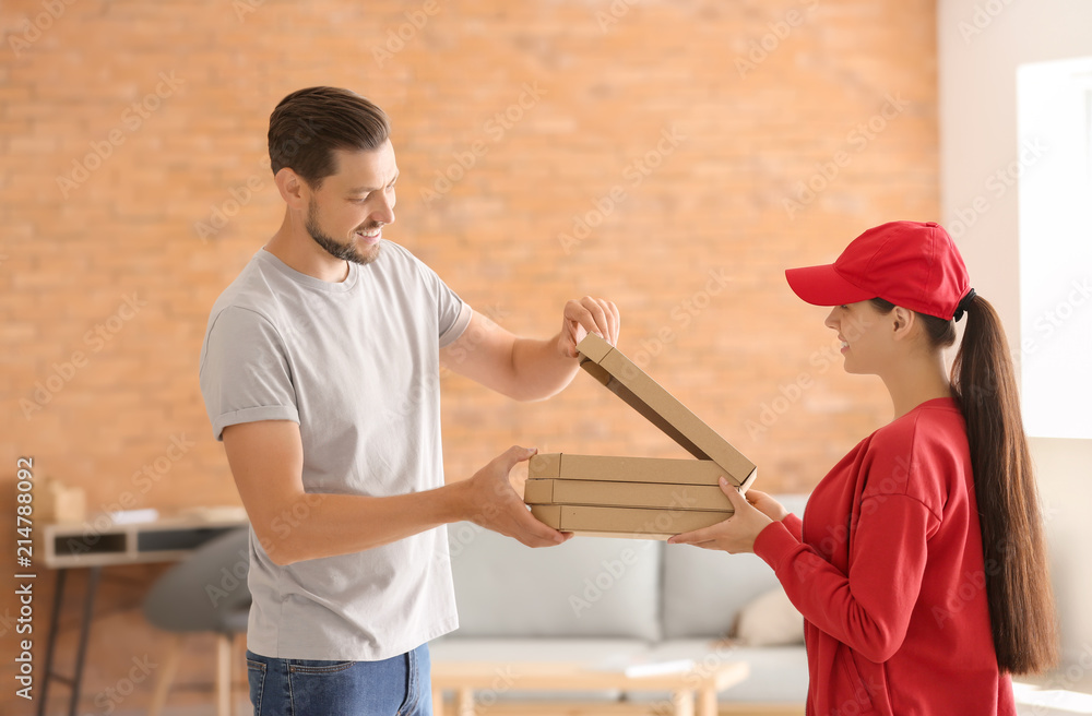 Young woman delivering pizza to customer indoors