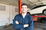 Fototapeta  - Smiling Worker Standing Arms Crossed In Auto Repair Shop