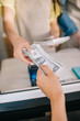 © LIGHTFIELD STUDIOS - cropped shot of customer giving dollar banknotes to worker in food truck
