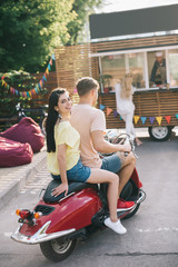 Canvas Print - happy couple sitting on scooter near food truck on street