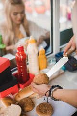 Canvas Print - cropped image of chef cutting bun with knife in food truck