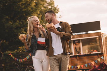 Sticker - low angle view of boyfriend feeding girlfriend with french fries near food truck