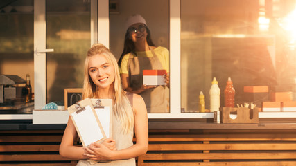 Sticker - attractive smiling chefs with menu looking at camera near food truck