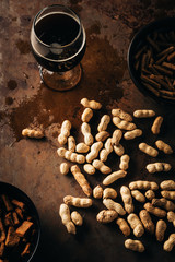 Wall Mural - top view of peanuts, baked breads and glass of beer on rust tabletop