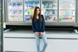 © AS Photo Family - Shopping woman looking at the shelves in the supermarket.  Portrait of a young girl in a market store taking seafood from fridge.