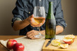 © Photoboyko - Beautiful ice cold glass and bottle of apple wine, with ripe apples in background. Male hands holding glass of premium cider on rustic wood table.