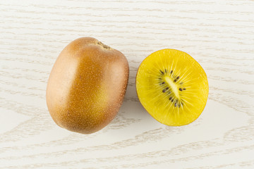 Wall Mural - Group of one whole one half of fresh golden brown kiwi fruit sungold variety flatlay on grey wood