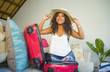 © TheVisualsYouNeed - young attractive and crazy happy latin American woman in beach Summer hat preparing suitcase leaving for holidays trip excited and messy about travel