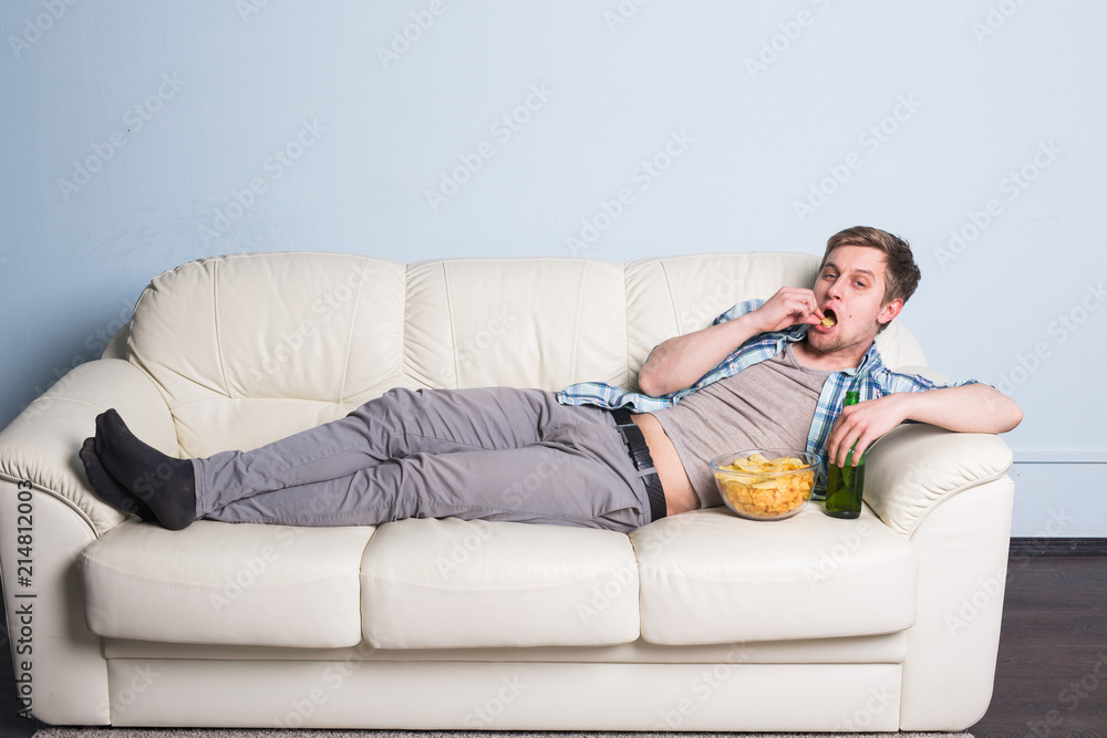 Man with beer and chips watching TV at home - obrazy, fototapety, plakaty 