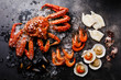 Boiled Seafood on ice - King Crab, Prawn Shrimp, Mussels Clams, Scallops in shells, Octopus mini, Squid on Grill on dark background