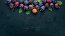 Fresh Plums With Leaves. Fruits. On A Black Wooden Background. Top View. Free Space For Your Text.