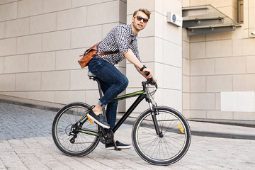 Fast vehicle. Smart handsome man riding a bike in the city while going to work in the office