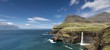 © imageBROKER - Cliffs with a waterfall near a village, Mykines Island at the rear, Gasadalur, Vagar, Faroe Islands, Denmark, Europe