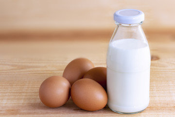 Prepare breakfast with eggs and milk on a wooden table.