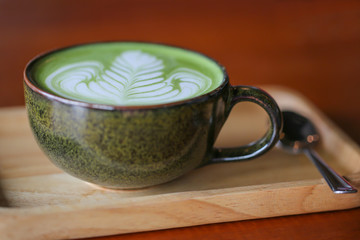 A cup of green tea latte on wooden table.