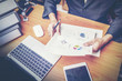 © chokniti - Businessmen are analyzed data from report using smartphone and laptop computer.