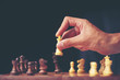 © chokniti - hand of businessman moving chess figure in competition success play. strategy, management or leadership concept