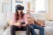 © Aleksei Lazukov - young woman  in virtual reality glasses with joystick and  young man on the couch