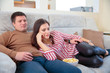 © Aleksei Lazukov - young couple watching television lying on sofa with popcorn