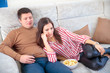 © Aleksei Lazukov - young couple watching television on sofa with popcorn at home