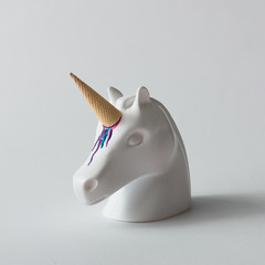 Wall Mural - white painted unicorn head with colorful ice cream horn on bright white background. minimal art fant