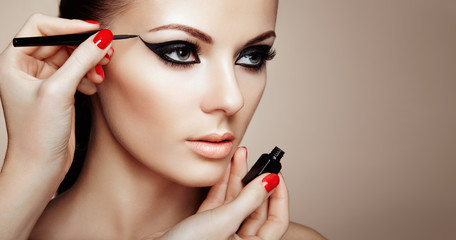 Wall Mural - makeup artist applies eyeshadow. beautiful woman make-up eye with black liner. fashion makeup arrows